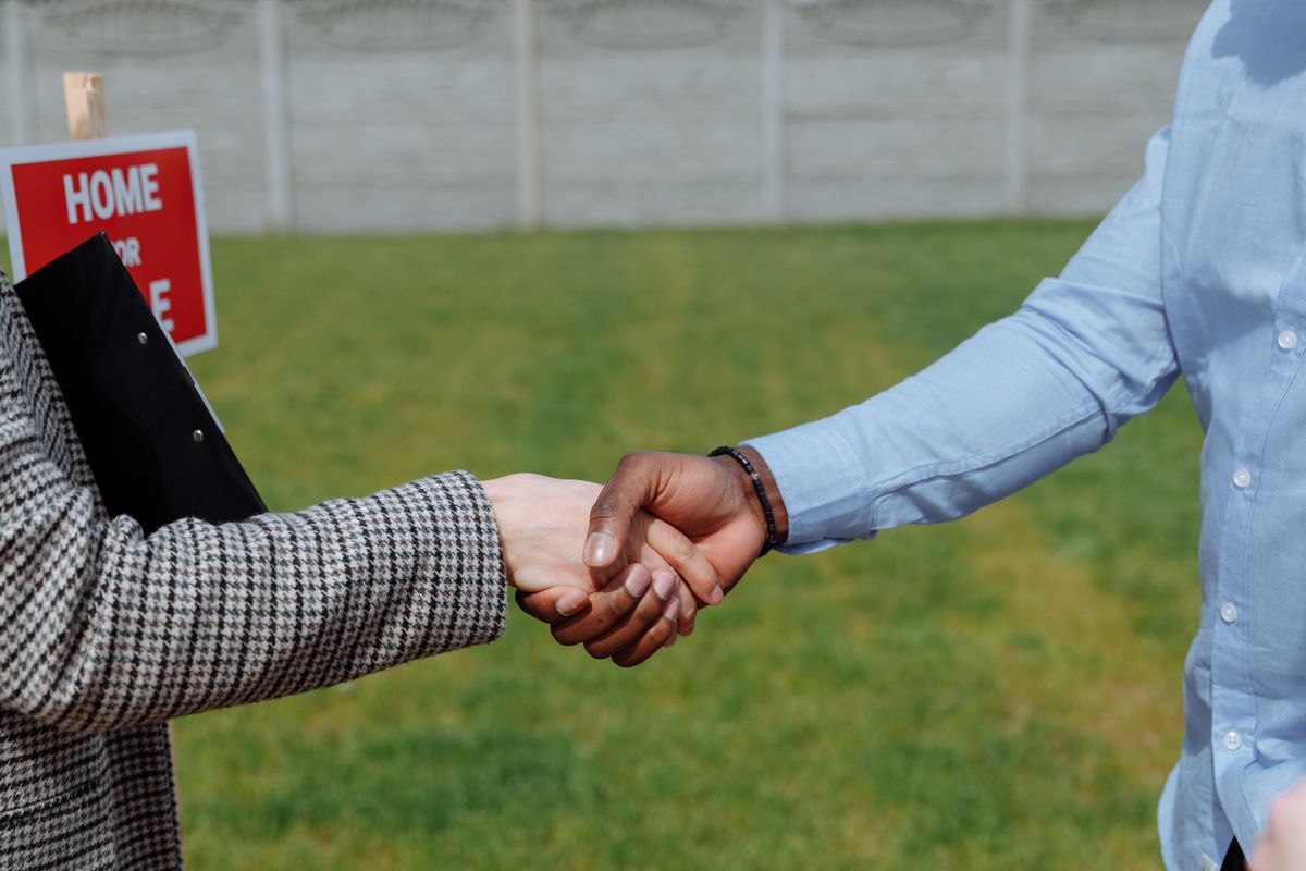 Buyers sealing a deal with a handshake outside a property
